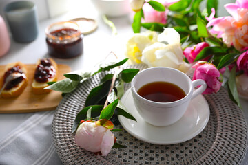 Beautiful peonies and cup of tea on table