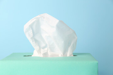 Box of paper tissues on light blue background, closeup