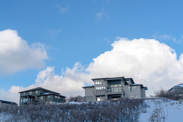 Blue sky and puffy clouds over homes on an inceredible mountain setting in winter
