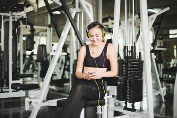 Fototapeta na wymiar Beautiful women come to exercise in the gym and are relaxed by listening to music from headphones. She wears a sportswear.