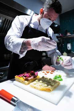 Vertical shot of a male chef wearing a face mask while preparing a delicious meal