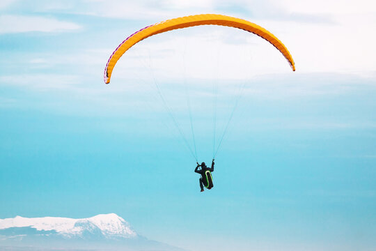 Paraglider flying in the sky and snowy mountains on background. Paragliding extreme sport 
