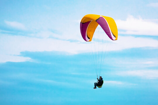 Paraglider in the sky. Bright paraplan flying in blue sky, space for text