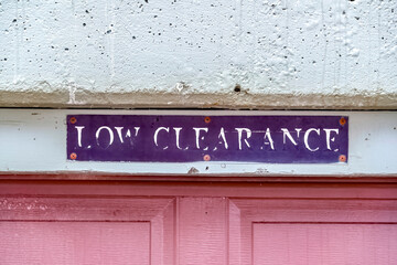 Low Clearance sign above the panelled red wooden garage door of a building