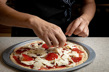 Male hands preparing pepperoni and mushrooms homemade pizza