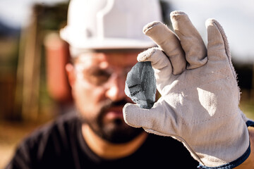 rough iron stone, ferrous metal nugget mined. Miner holding hematitia stone. Spot focus.