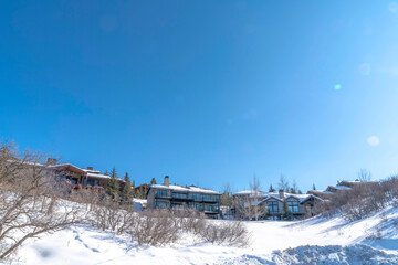 Fototapeta na wymiar Houses on snowy hill terrain in Park City Utah with clear blue sky background
