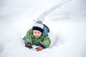 Fototapeta na wymiar boy crawls on a snow mountain