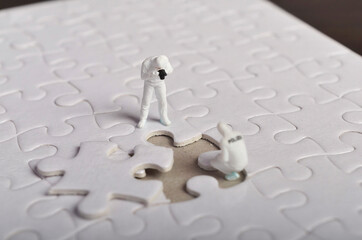 Miniature people ; Crime Scene Investigation with missing jigsaw puzzle. Selective focus.