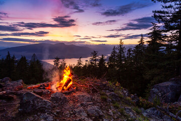 Warm Camp Fire on top of a mountain with Beautiful Canadian Nature Landscape in background during a...