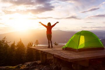 Adventure Girl and Camping Tent on top of a Mountain with Canadian Nature Landscape in the Background during colorful sunset. Taken on Bowen Island, near Vancouver, British Columbia, Canada.