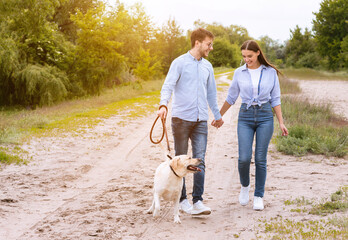 Cute couple and labrador walking together in countryside