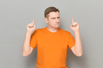 Portrait of serious disgruntled man raising both index fingers up