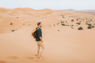 Man backpacker travel in Morocco, Sahara desert. Explore african nature, sand dunes around. Freedom and lifestyle concept.