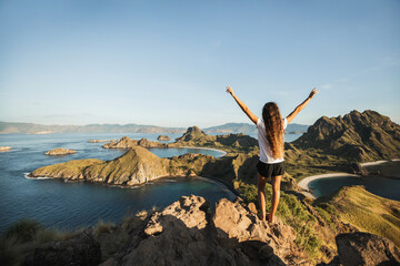 Fototapeta na wymiar Woman with amazing view of Padar island in Komodo national park, Indonesia. Enjoying tropical vacation in Asia. Lifestyle travel concept. View from behind.