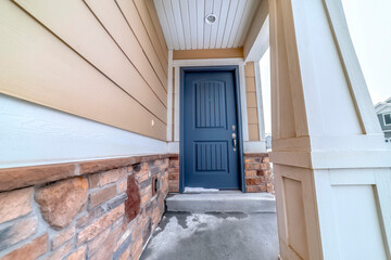 Home facade with blue panel door and melting snow on the doorstep and entryway