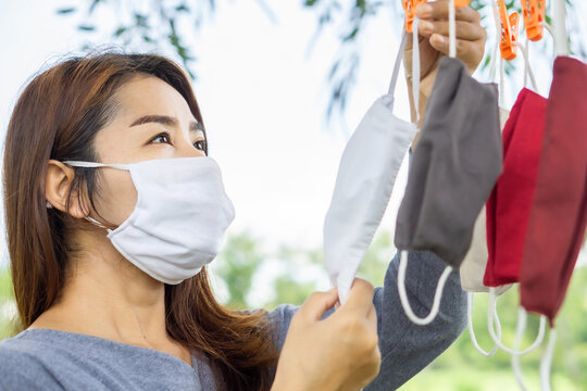 Asian Woman Washing Fabric Face Mask And Hanging To Dry Outdoor, New Normal During Covid-19 