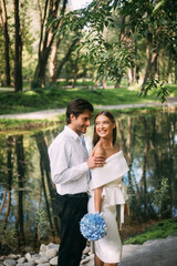 Newly-Wedded Couple In Love Hugging In Beautiful Park Near Lake
