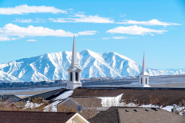 Modern spires of church with steep snowy mountain and sunny blue sky background