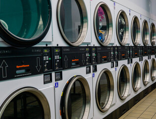 Empty Laundromat - Line of large clothes dryers top and bottom, some with clothes in them.