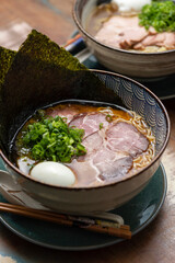 asian ramen with pork meat noodles chive broth egg and nori on a traditional bowl with colorful shallow background