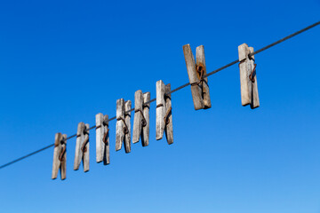 clothespin for drying clothes on a rope in different positions against a blue sky