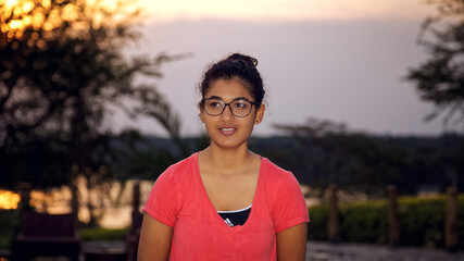 a happy young Asian girl on pool side looking away, amazing sunset in summer.