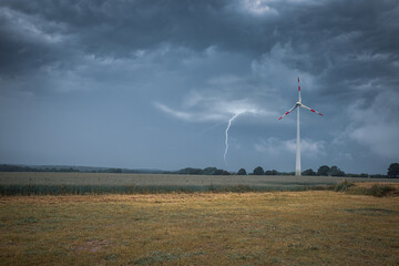 Fototapeta na wymiar a lightning strikes the ground next to a wind turbine