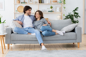 Couple in love hugging on sofa, looking at each other