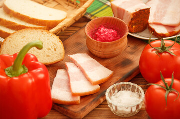 Pork jowl bacon with fresh vegetables for sandwich cooking. Colorful food photo with fresh vegetables and lard slices.