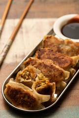 gyoza on silver plate wooden table chopsticks and soy sauce