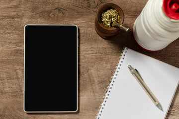 Escritorio de madera con tableta con pantalla en negro,  libreta, bolígrafo, yerba mate y temo...