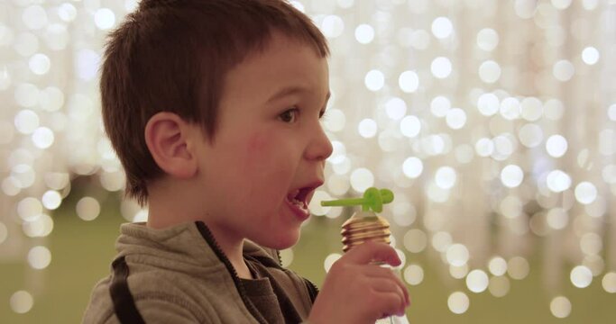 Toddler boy sipping drink from bendy straw at light show - close up on face