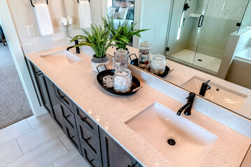 Two sinks with black faucet on white countertop over cabinets on tile floor