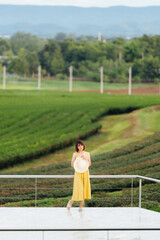 Beautuful Asian woman wear yellow dress walking in tea field.