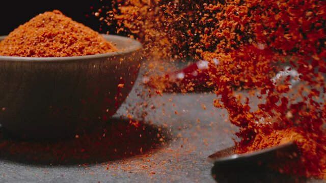 Cayenne pepper powder. Spoon with dry chili falls down with a splash. SLOW MOTION