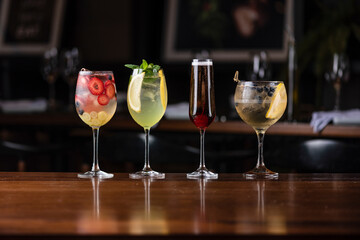 four different colorful drinks on a wooden table at a fancy restaurant bar with blurred background