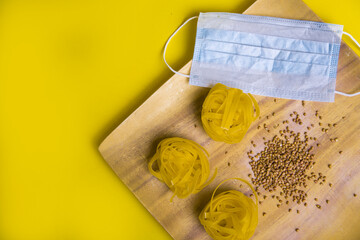 Buckwheat and pasta, medical mask in wooden plates. Slow carbs with copy space. Italian and Russian cuisine. food delivery in self-isolation. staying at home, we take care of our health. prevention