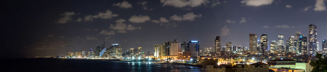 Fototapeta na wymiar Panoramic view at night. Seascape and skyscrapers on background in Tel Aviv, Israel.