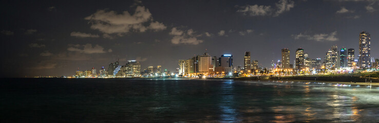 Fototapeta premium Panoramic view at night. Seascape and skyscrapers on background in Tel Aviv, Israel.