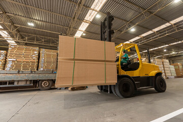 wood pallet forklift driving at a factory floor inside a shed loading a truck
