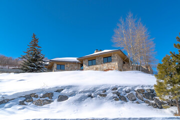 Stone home with snowy hip roof on a hill in Park City Utah viewed in winter