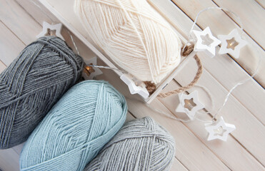 Fototapeta na wymiar Wool yarn milky, gray, mint color lie on a light wooden table