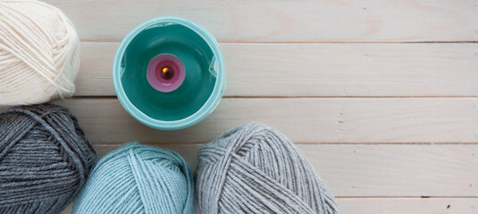 Wool yarn milky, gray, mint color lie on a light wooden table