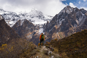 Fototapeta premium Young trekker standing on top of the hill and looking to snow Himalaya mountains range in Manaslu circuit trekking route in Himalaya mountains, Nepal