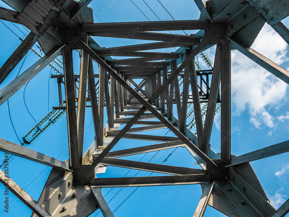 Wall mural The metal tower structure of a high-voltage power lines from the inside, bottom view, against the blue sky