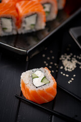 Traditional fresh Japanese Philadelphia sushi rolls on a black wooden background