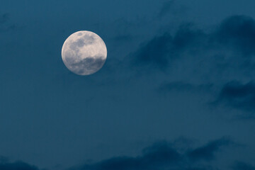 Fototapeta na wymiar A full moon in a cloudy blue sky background