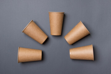Eco-friendly cardboard cup lie on a gray color paper background. Mock-up. Close-up. The concept of...