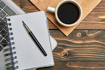 Laptop cup with coffee notebook pen on wooden with roofing. Working table view from the top.